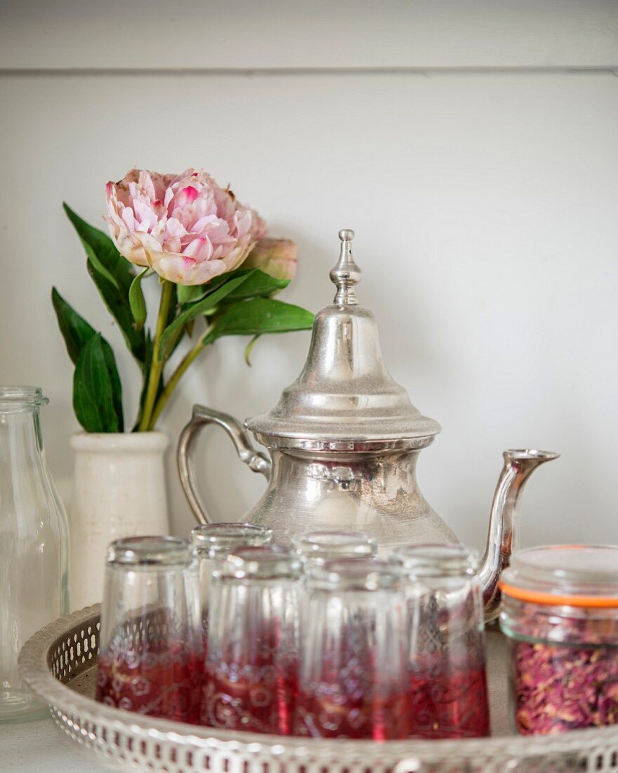 Silver teapot, Oriental tea glasses and peony in vase on tray