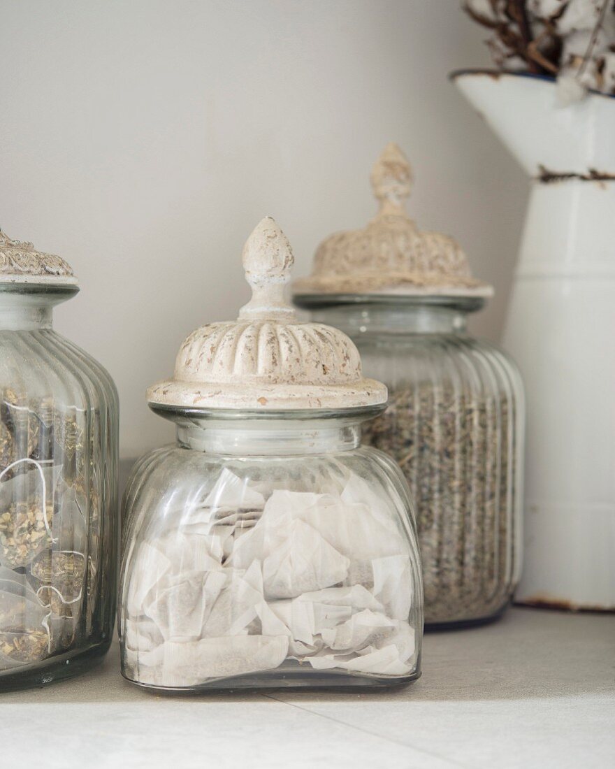 Vintage jars with patinated lids and enamel jug in background