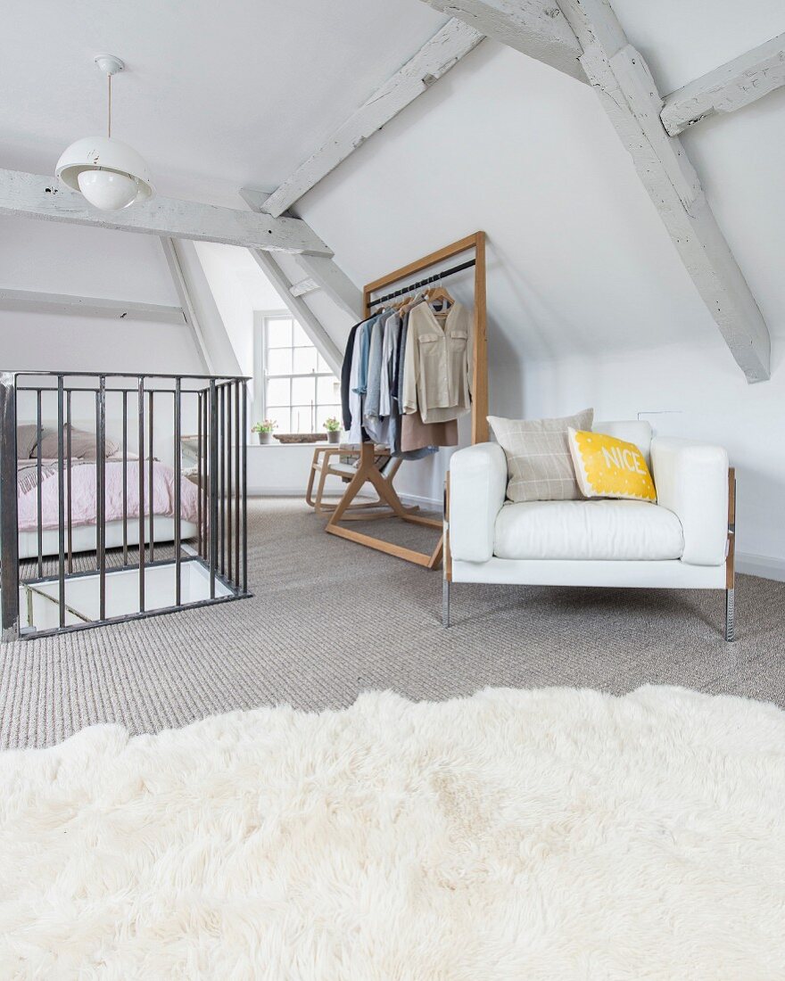 Bedroom in converted attic with retro designer armchair and clothes rail