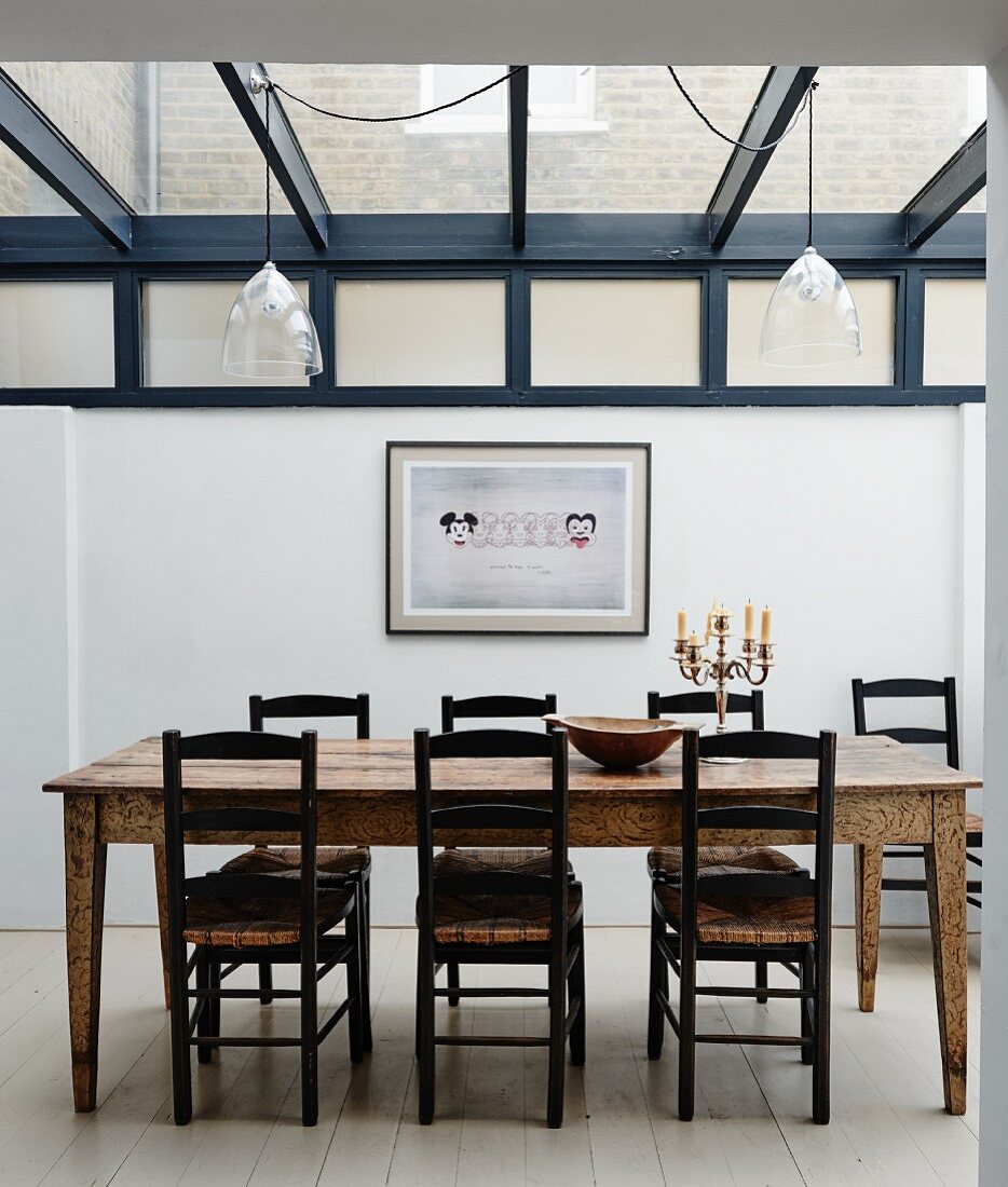 Rustic wooden dining table and chairs in extension with glass roof