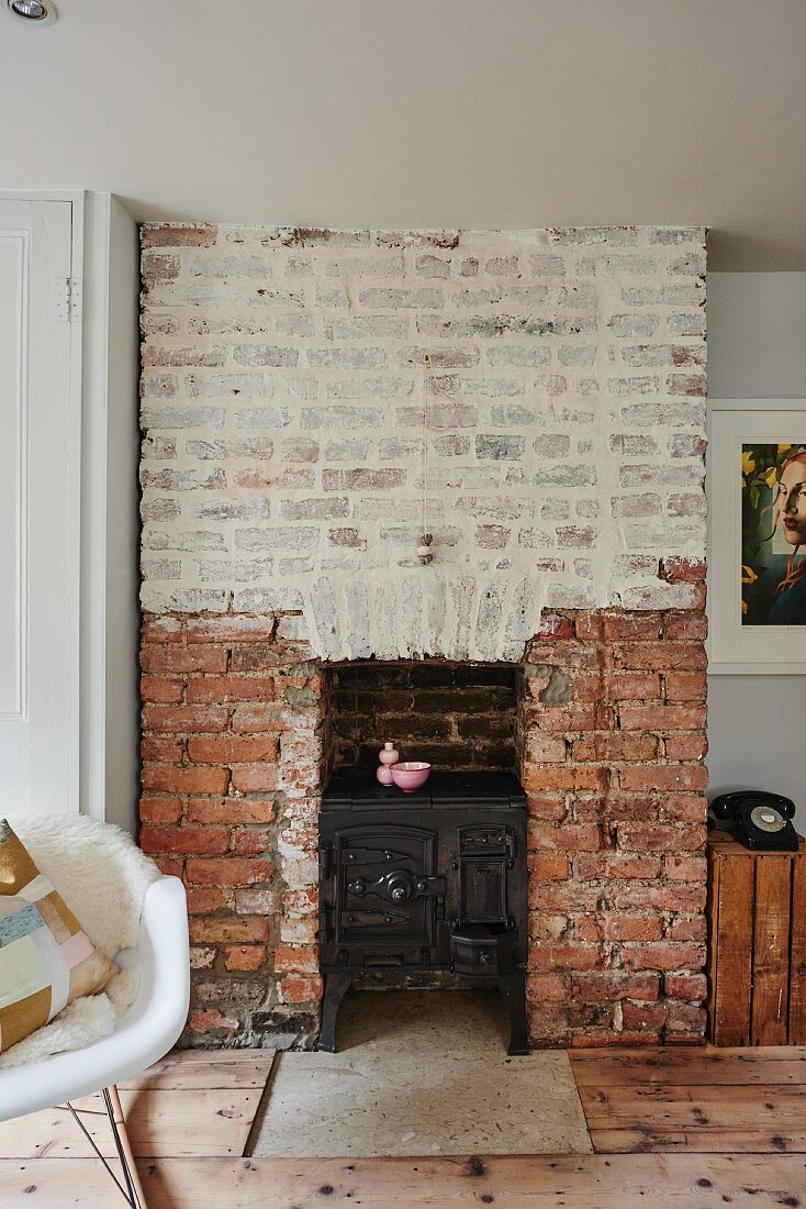 Cast iron stove in old brick fireplace with whitewashed upper section in living room