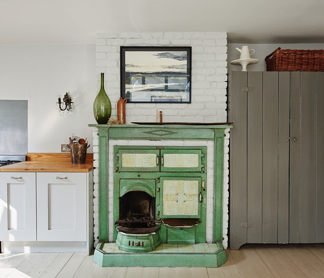Vintage range in masonry fireplace painted green next to kitchen counter in rustic interior