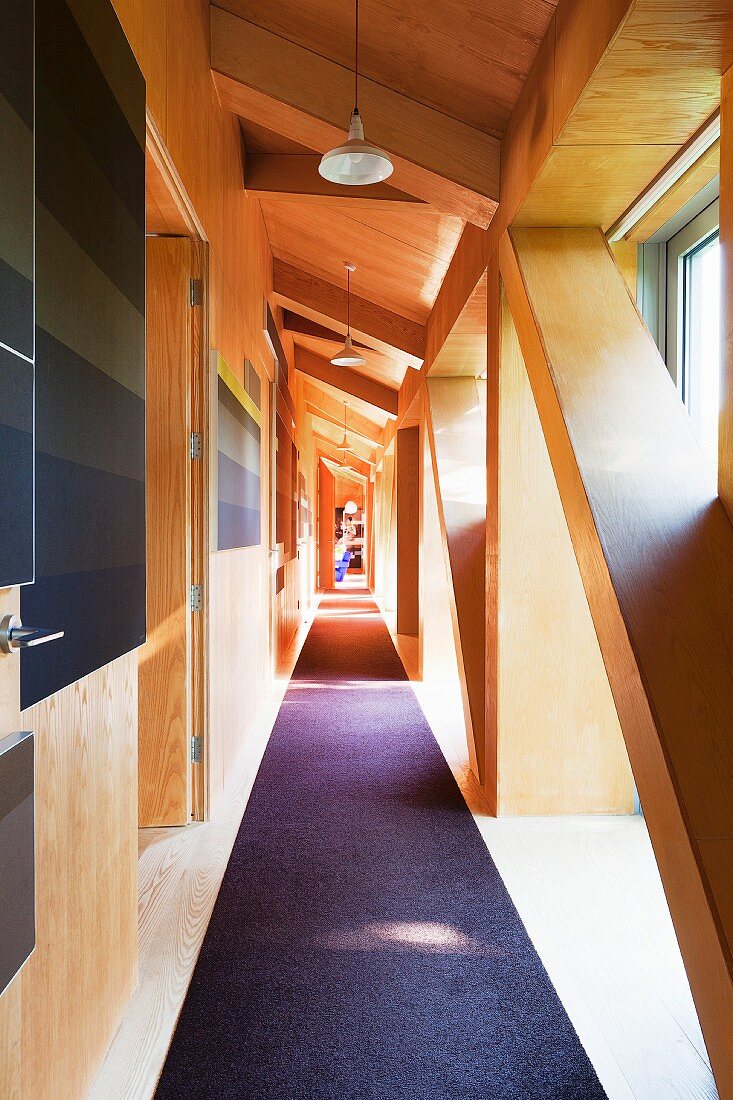 Corridor with dark runner and wooden structure behind glass façade