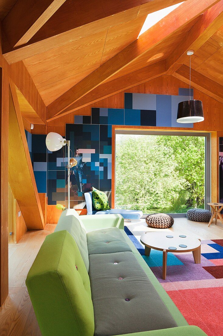 Designer-Sofa mit verschiedenen Grüntönen auf Bezug, in modernem, holzvertäfeltem Wohnraum