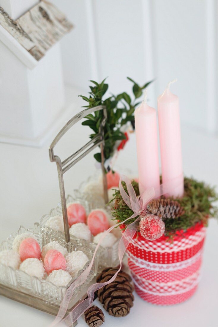 Candles festively arranged in glass decorated with red and white ribbons
