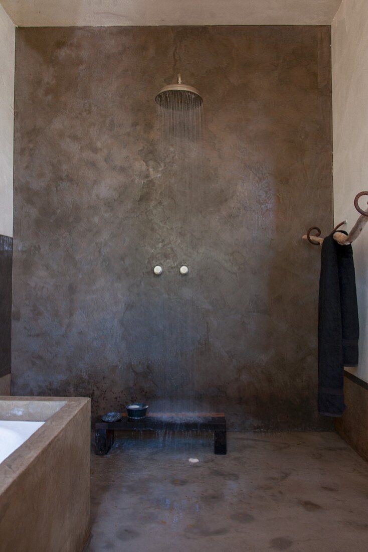 Dusche im Ethnostil mit grau verputzten Wänden und prasselndem Wasser