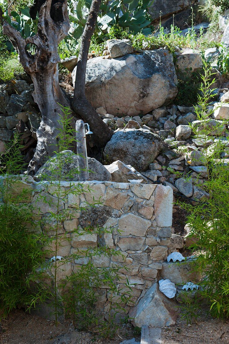 Outdoor shower on wall at foot of boulder-covered slope