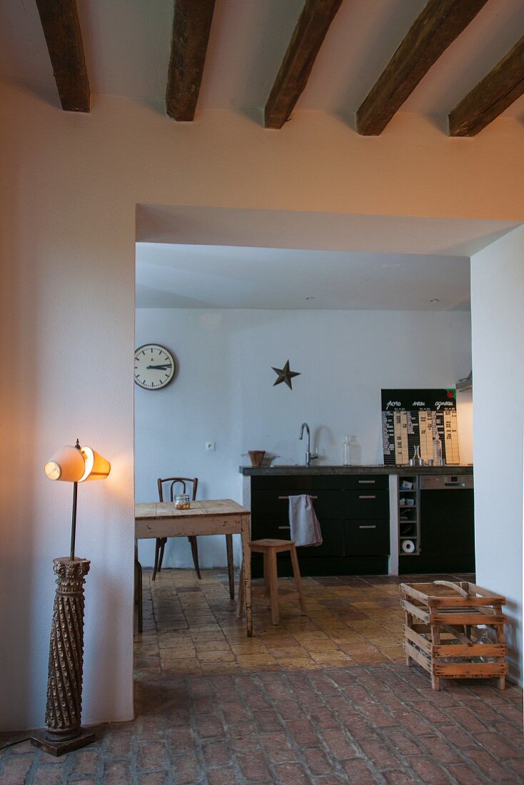 Standard lamp next to wide, open doorway with view of kitchen table and counter