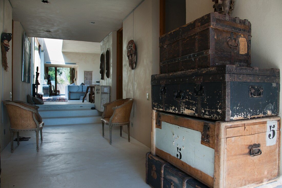 Stack of old steamer trunks in foyer of bungalow with view into interior