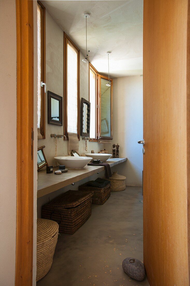 Blick in ein Badezimmer im Ethnostil mit verschiedenen Körben unter dem Waschtisch