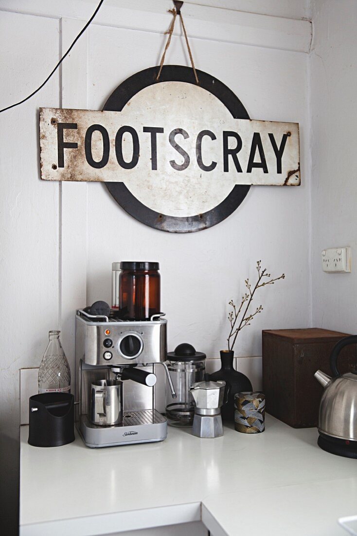 Vintage Schild über verschiedenen Kaffeemaschinen auf Küchenzeile