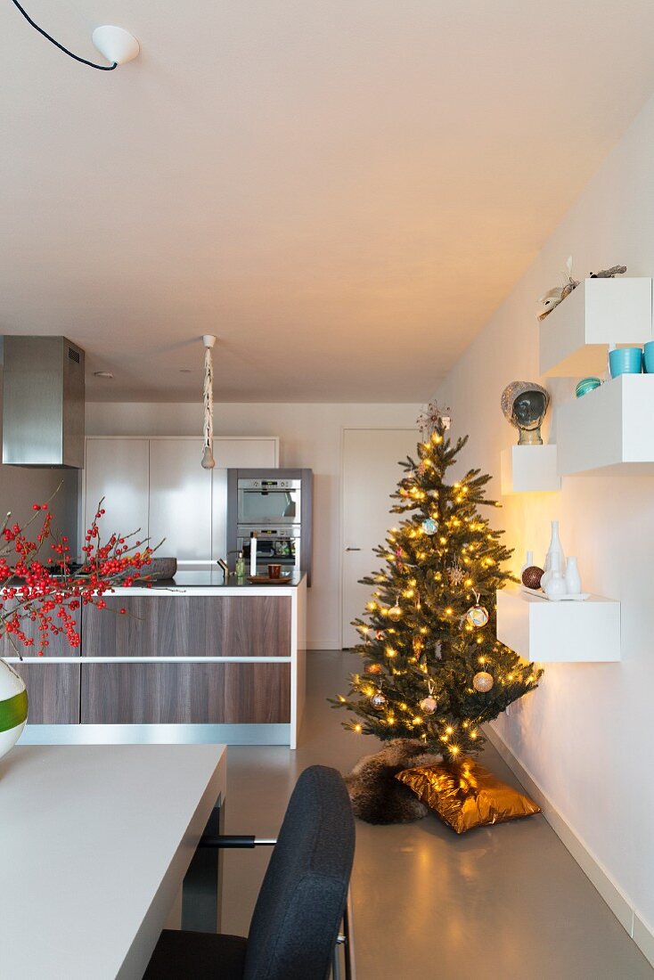 Brightly lit Christmas tree in modern, open-plan kitchen