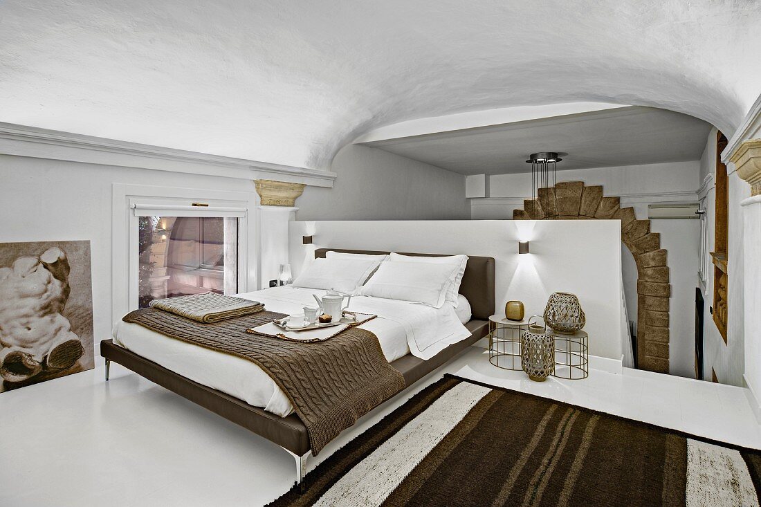 Eleganter Schlafbereich mit modernem Doppelbett und Gewölbedecke