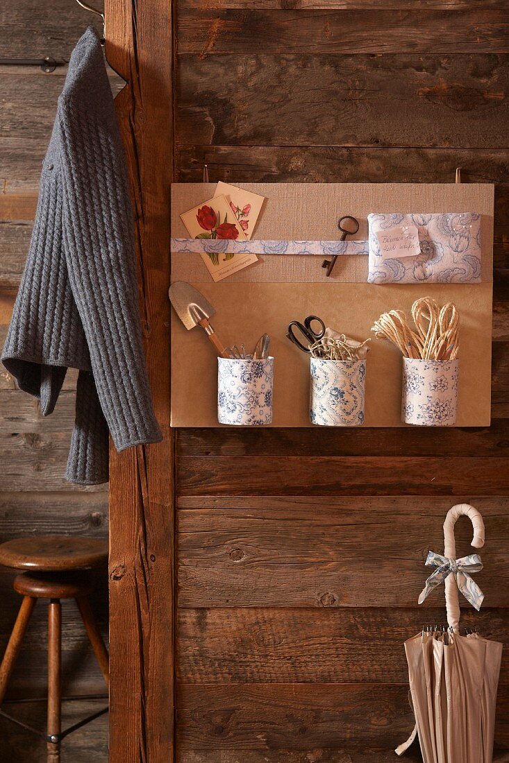 Metal containers covered in toile de jouy fabric attached to hand-made pinboard