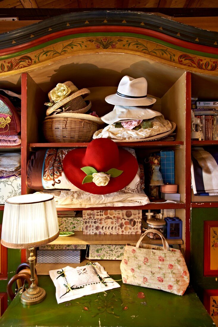 Romantische Hüte und dekorative Schachteln in altem Bauernschrank