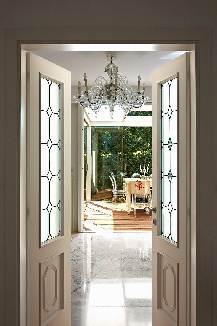 Open double doors with leaded glass panels and view of elegant marble floor and dining set