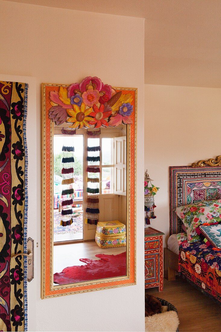 Schlafzimmer im Folklorestil mit einem bunt bemalten Spiegel und gemustertem Bett