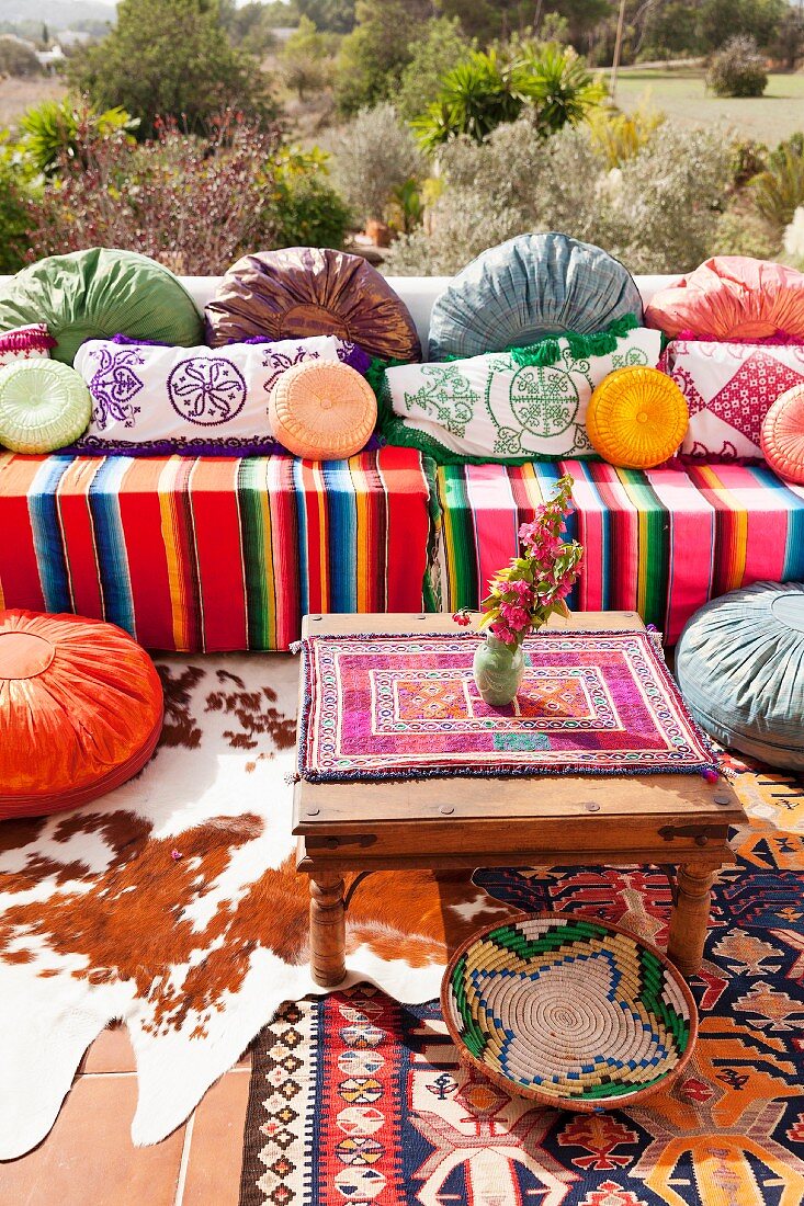 Gemütlicher Outdoor Sitzbereich im bunten Hippie-Stil mit verschiedenen Ethno-Kissen und Decken