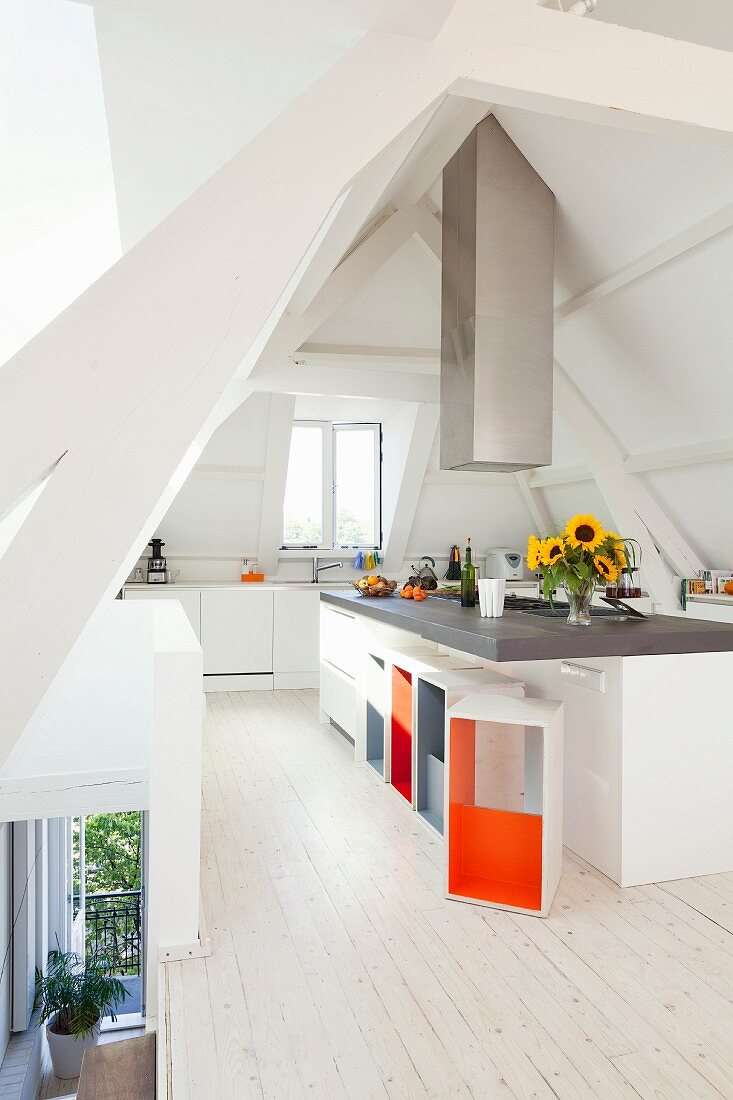 Island counter and designer stools with brightly painted inner surfaces in attic kitchen