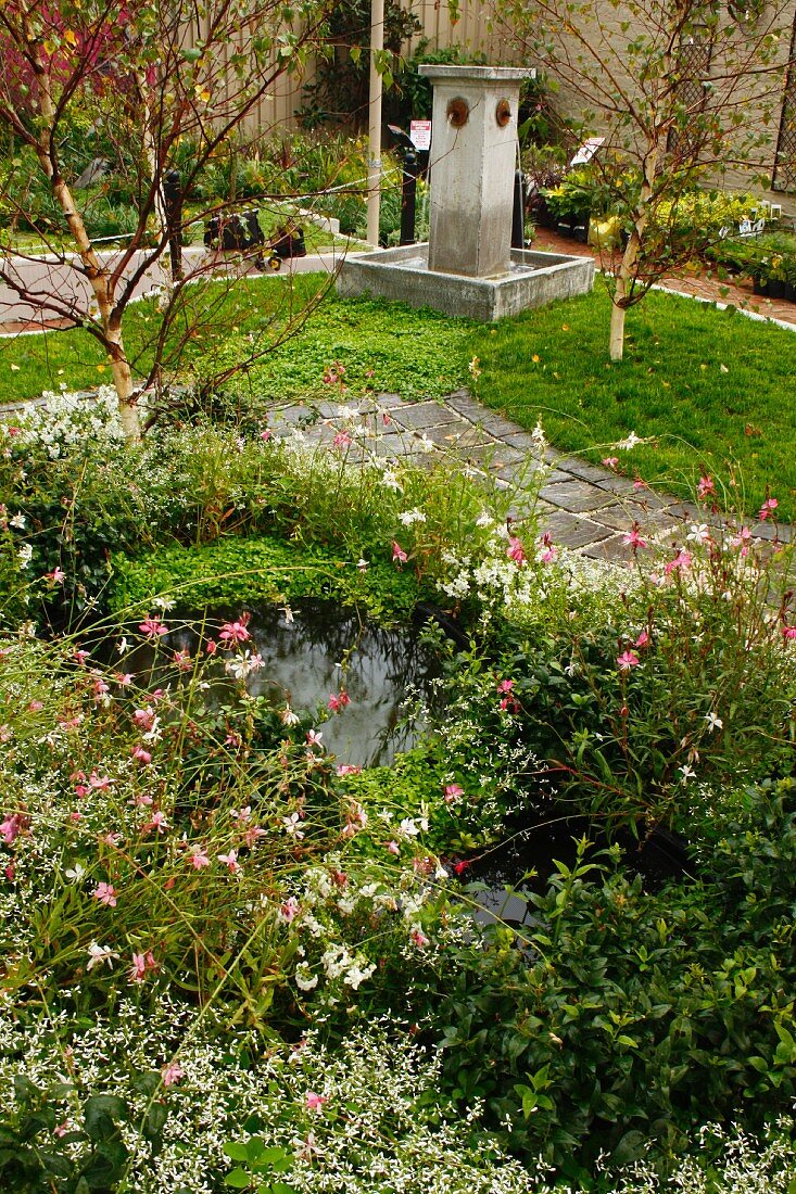 Steinbrunnen & kleine dichtbepflanzte Wasserteiche neben Gartenweg