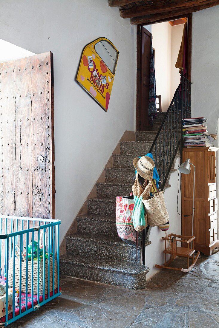 Playpen on stone floor at foot of staircase in foyer
