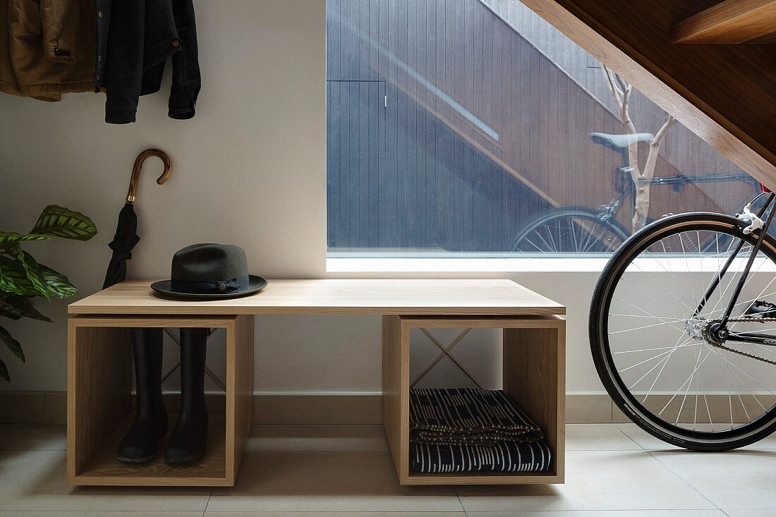 Schlichtes, modernes Garderobenmöbel mit Herrenhut und Fahrrad im Flurbereich