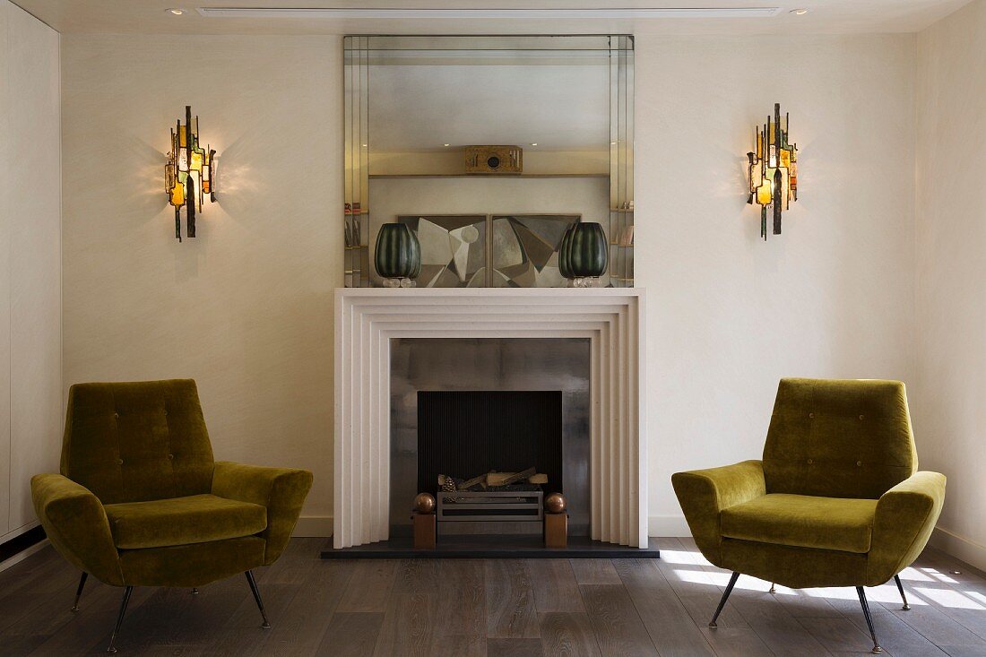 Objets d'art on mantelpiece of fireplace with postmodern surround flanked by hand-crafted sconce lamps and two retro armchairs