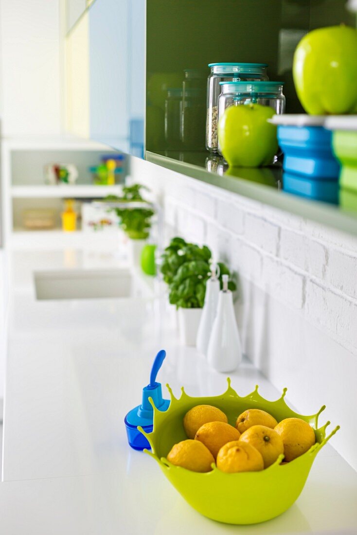 Blau- und Grüntöne im Hängeschrank und auf der Spülentheke einer weissen Küchenzeile