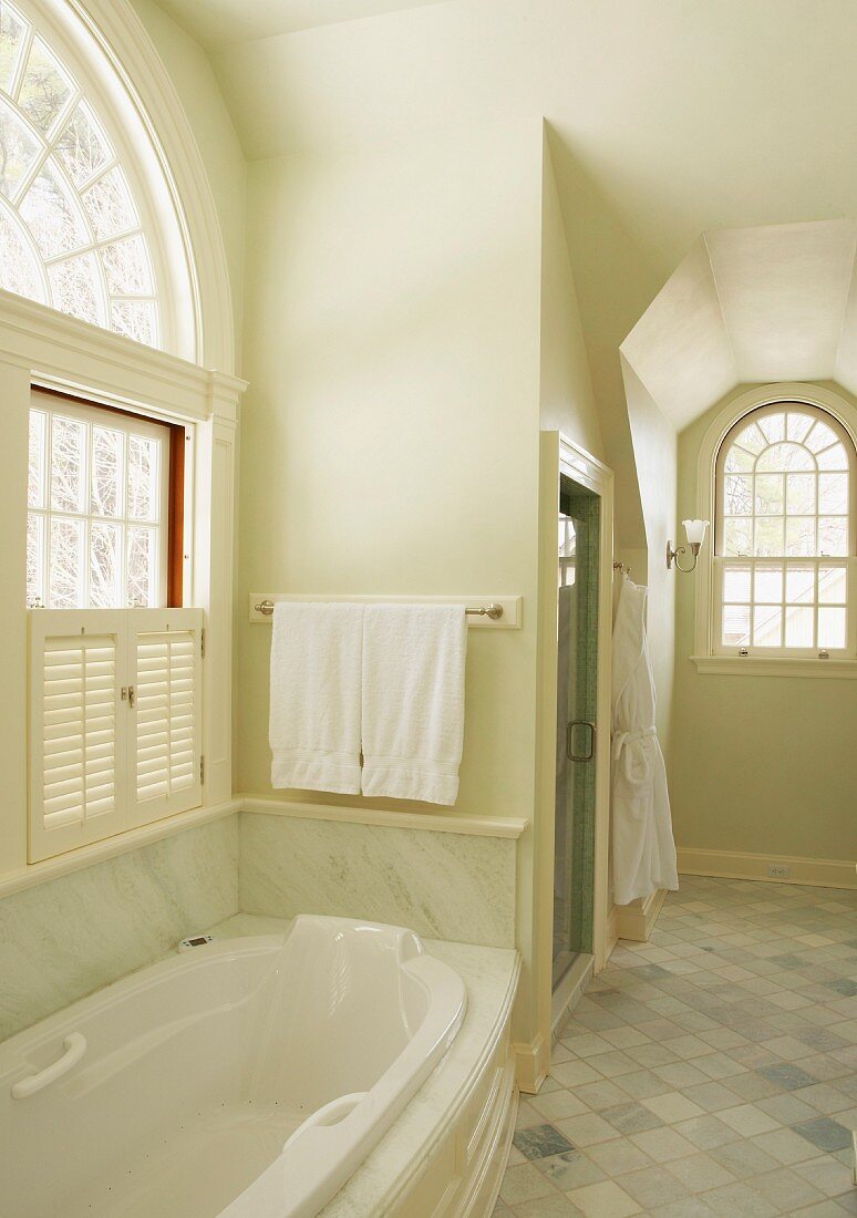 Country-house bathroom with marble cladding and arched windows