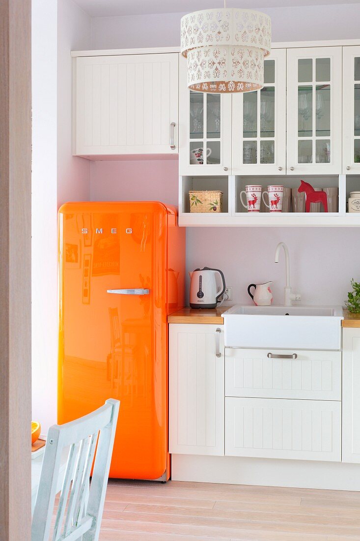 Orangefarbener Retro-Kühlschrank als Farbakzent in weisser Landhausküche