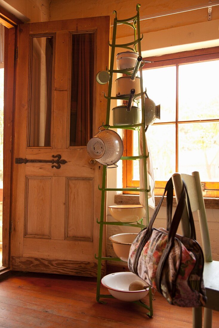 Kitchen utensils hung on green bottle rack in rustic kitchen