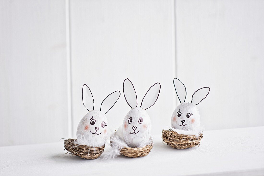 Three blown eggs made into Easter bunnies arranged in baskets