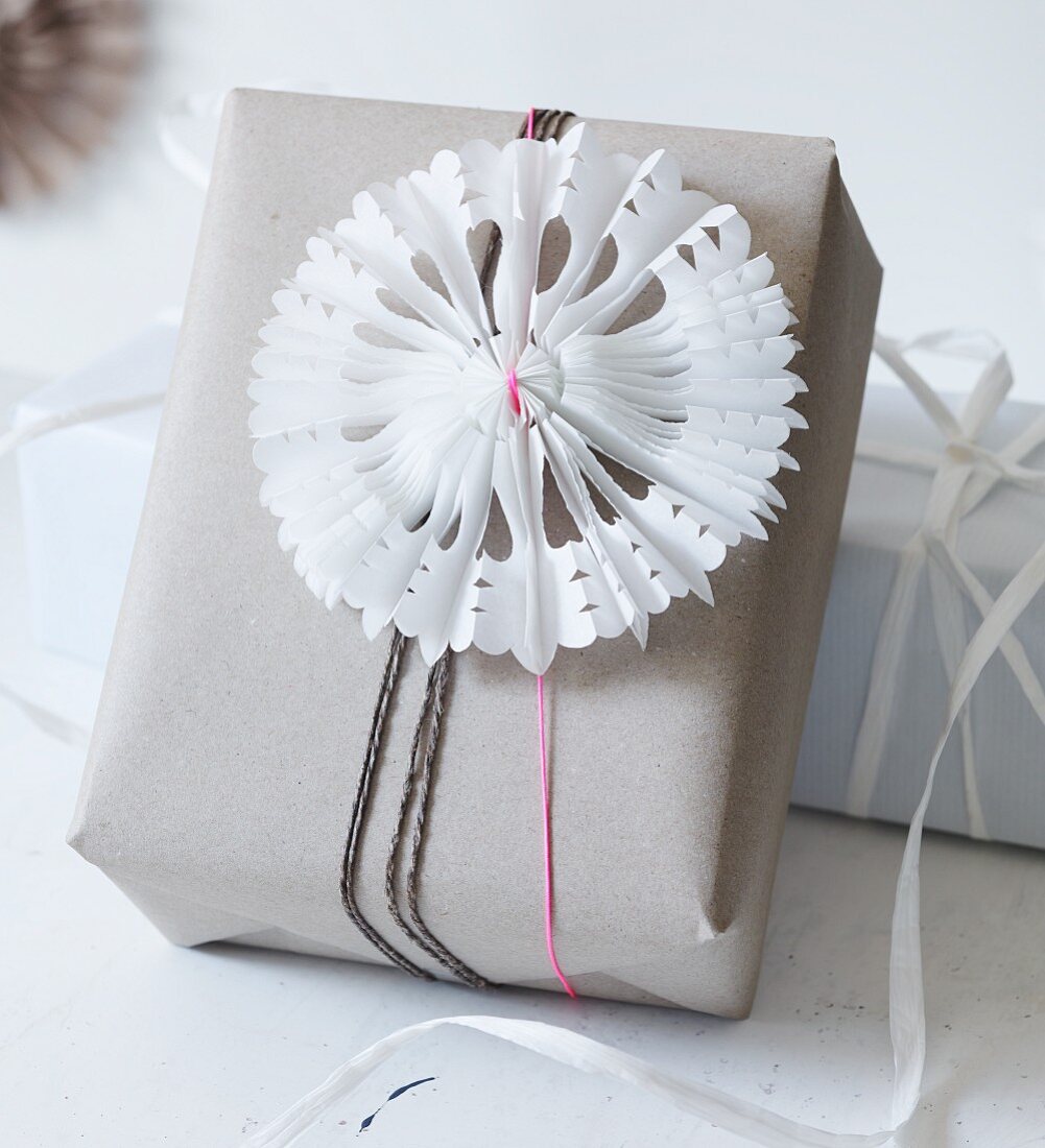 Selbstgebastelter Papierstern mit Scherenschnittmuster und Plisseefaltung als Deko für Weihnachtspäckchen