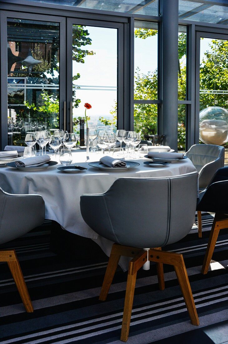 Armlehnstühle mit lederbezogener Sitzschale um festlich gedeckten Tisch auf Terrasse