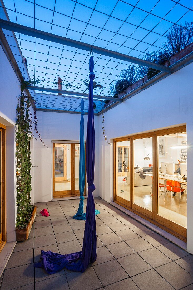 Twilight atmosphere; courtyard of town house with knotted fabric climbing ropes and view into study