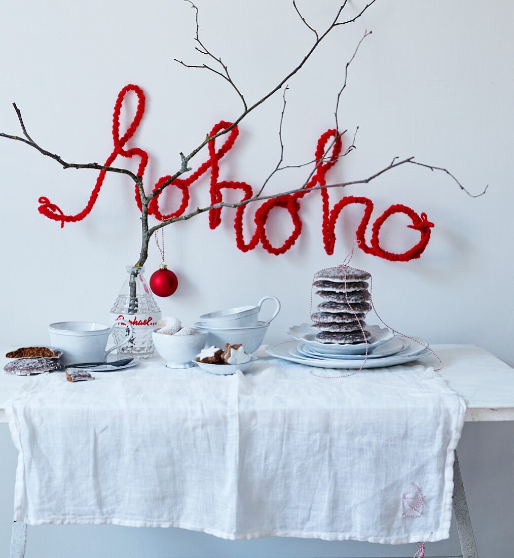 Weihnachtliches Buffet mit einem Zweig und Schrift aus umhäkeltem Draht Hohoho