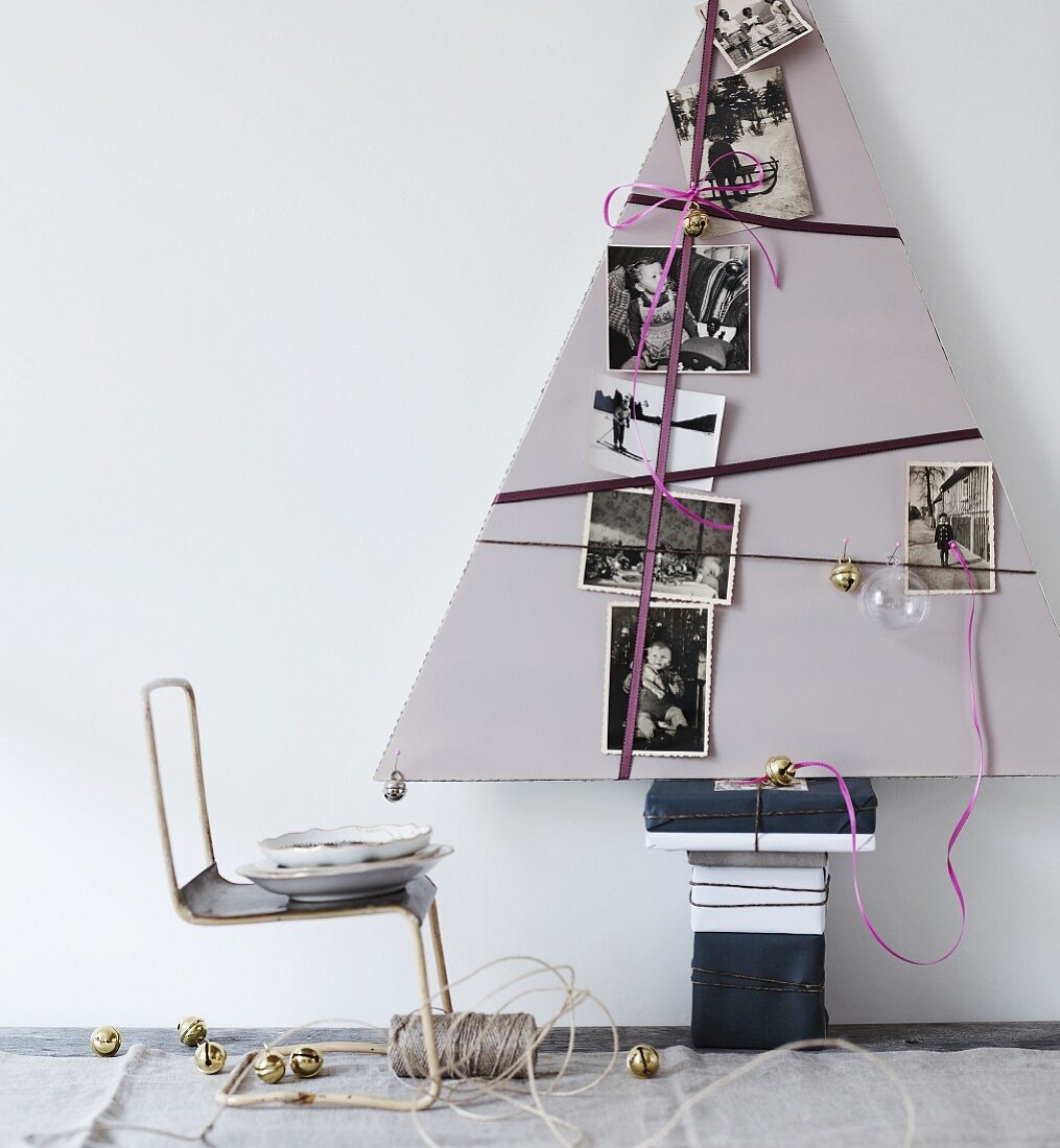 Stilisierter Weihnachtsbaum aus dreieckiger Pappe mit Geschenkbändern und schwarz-weissen Familienfotos