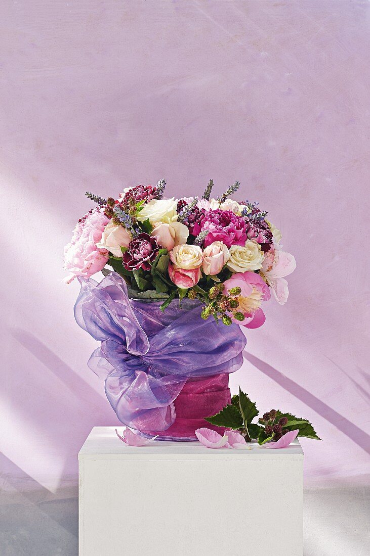Rosenstrauss mit Pfingstrosen, Lavendel und Brombeerzwiegen, festlich mit lilafarbenem Tüll dekoriert