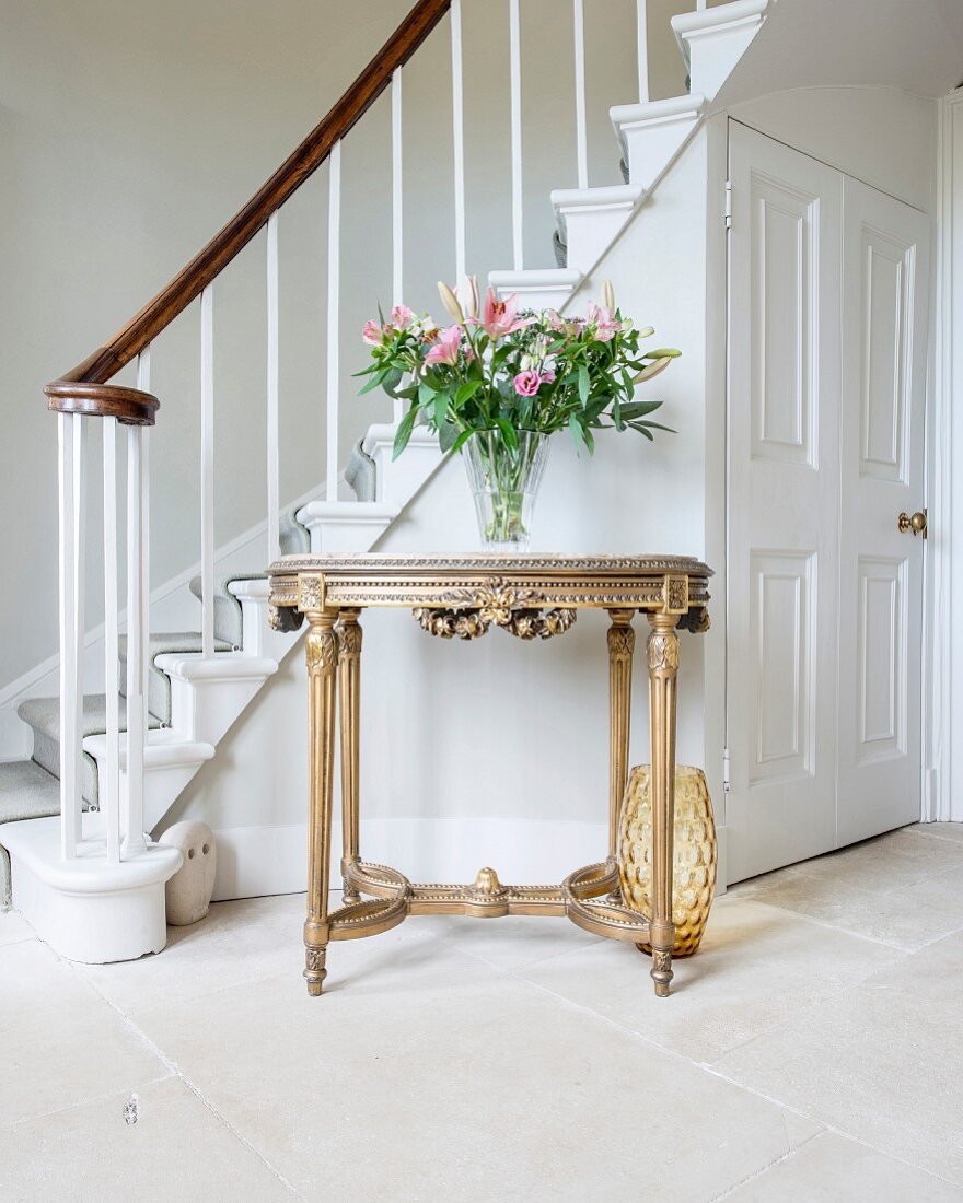 Neoclassical-style, gilt console table at foot of staircase in foyer