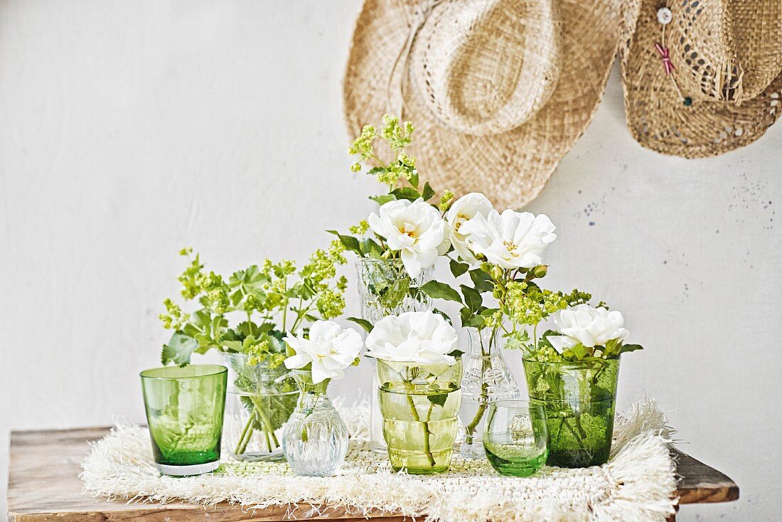 Lady's mantle & white garden roses in various glasses & vases