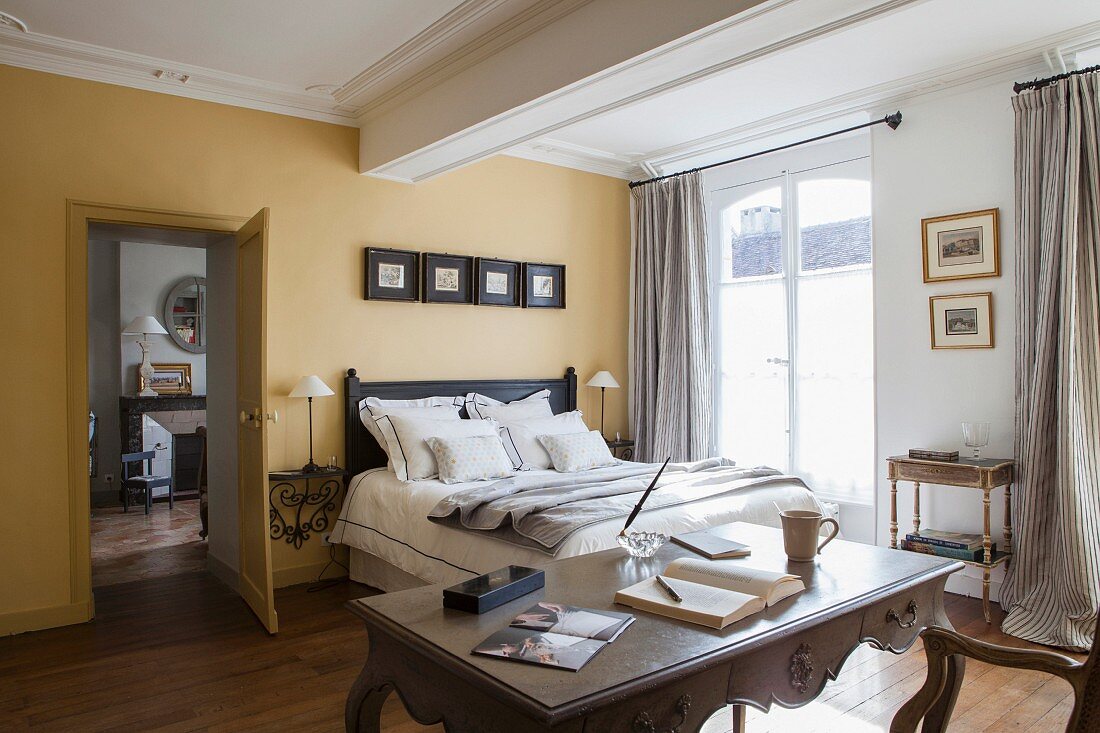 Bedroom with yellow walls, double bed and antique desk