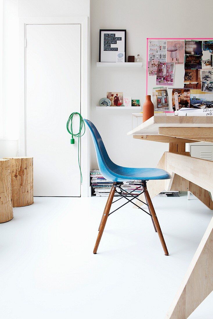 Blauer Eames-Stuhl in einem modernen Arbeitszimmer mit Holzmöbeln und Moodboard