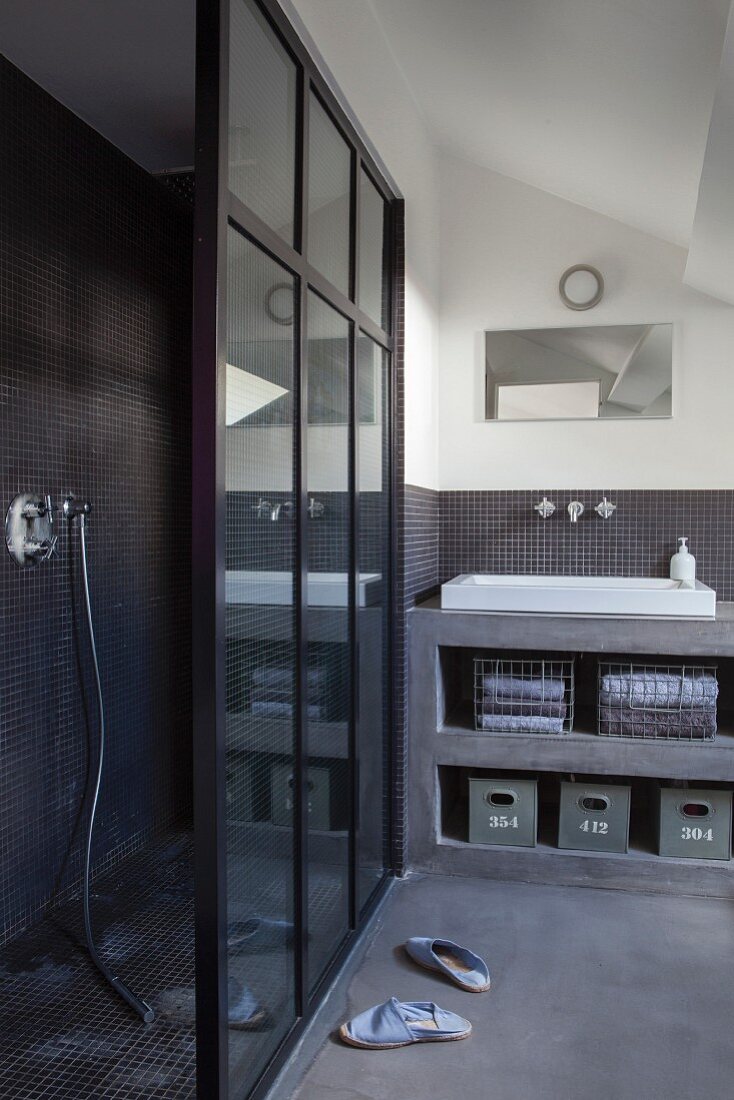 Grey bathroom with separate shower area and open-fronted concrete shelves with integrated sink