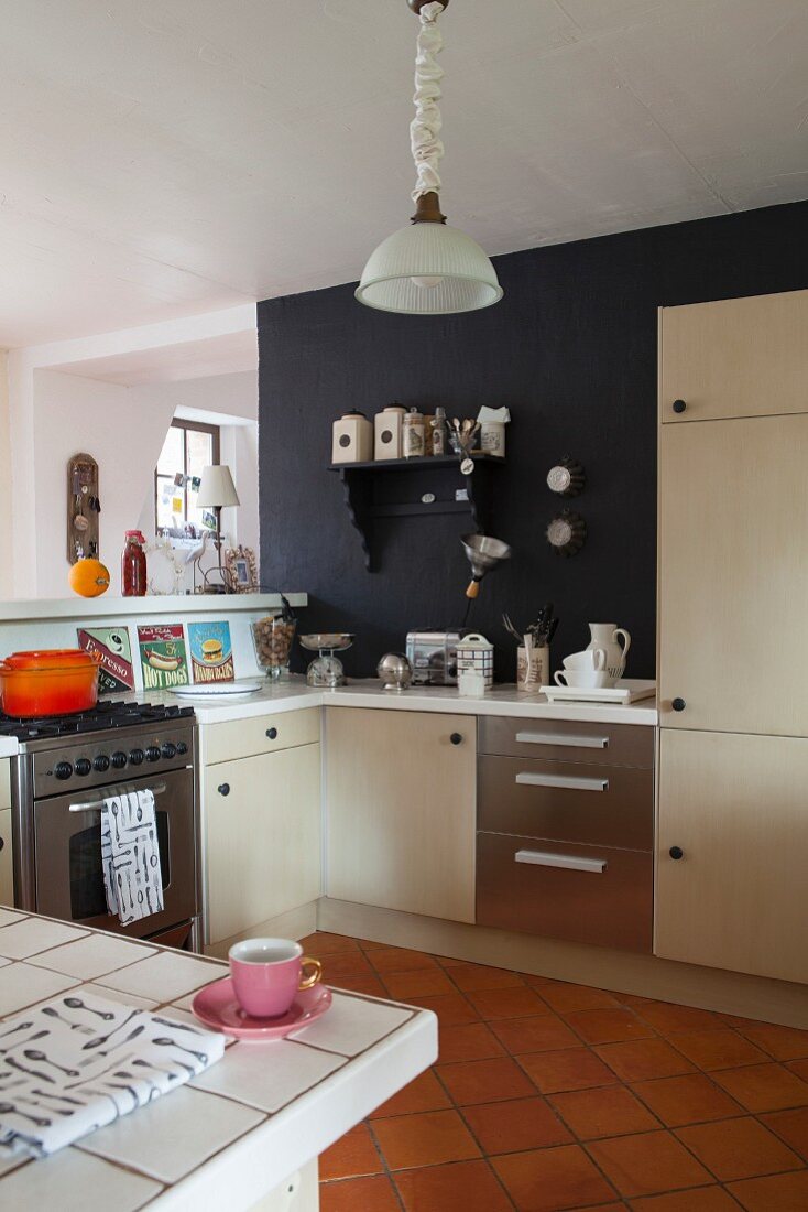Offener Küchenbereich mit moderner Einbauküche, hellen Schrankfronten und teilweise schwarz getönter Wand