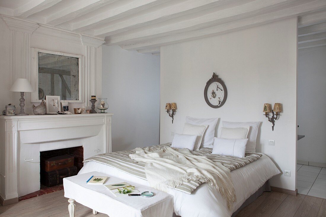 Ländliches Schlafzimmer in Weiß mit offenem Kamin und Bad Ensuite hinter Raumteiler