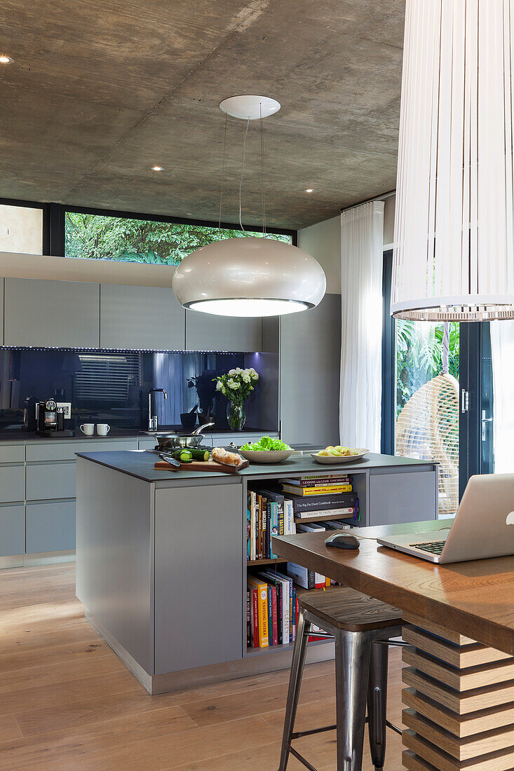 Moderne Küche mit Kochinsel, Hängeleuchte und Sichtbetondecke