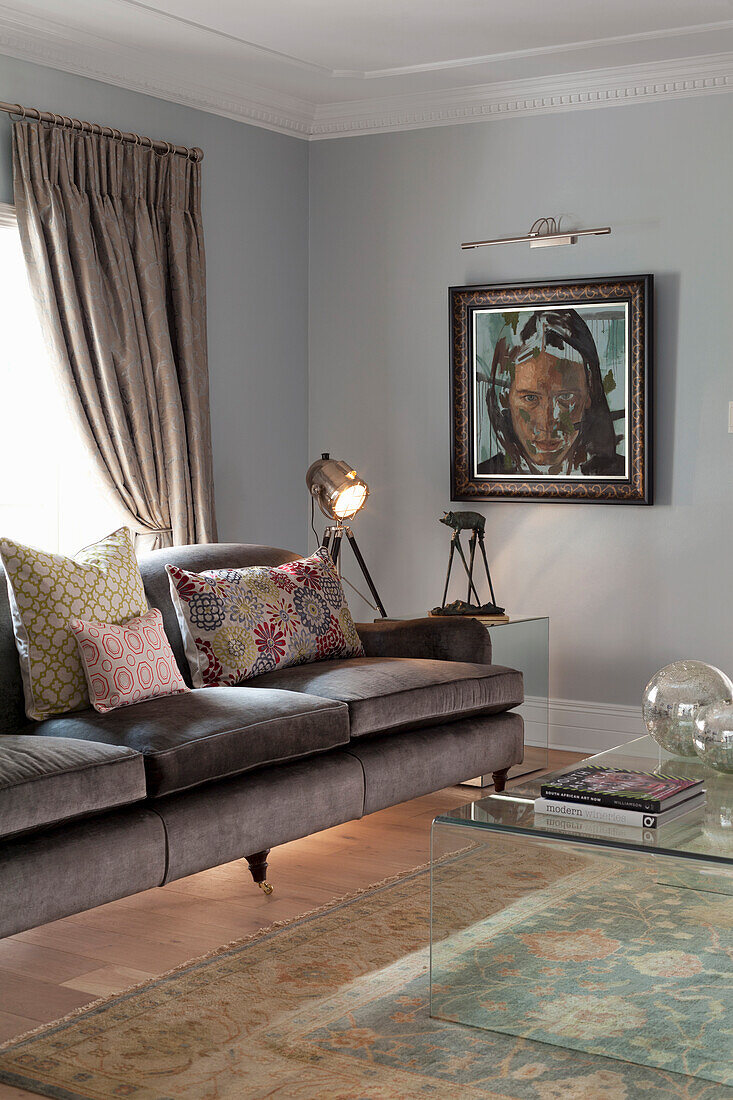 Dark grey velvet sofa with cushions and floor lamp in the grey-painted living room