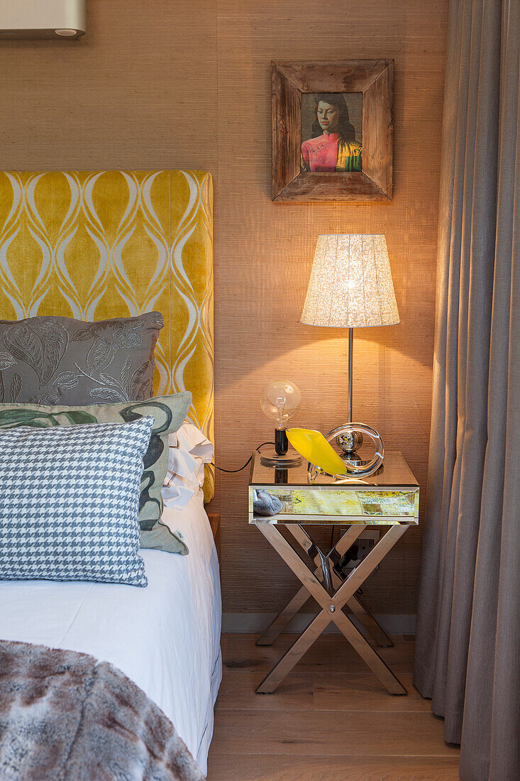 Bett mit gelbem Musterkopfteil und Beistelltisch mit Lampe, Schlafzimmer