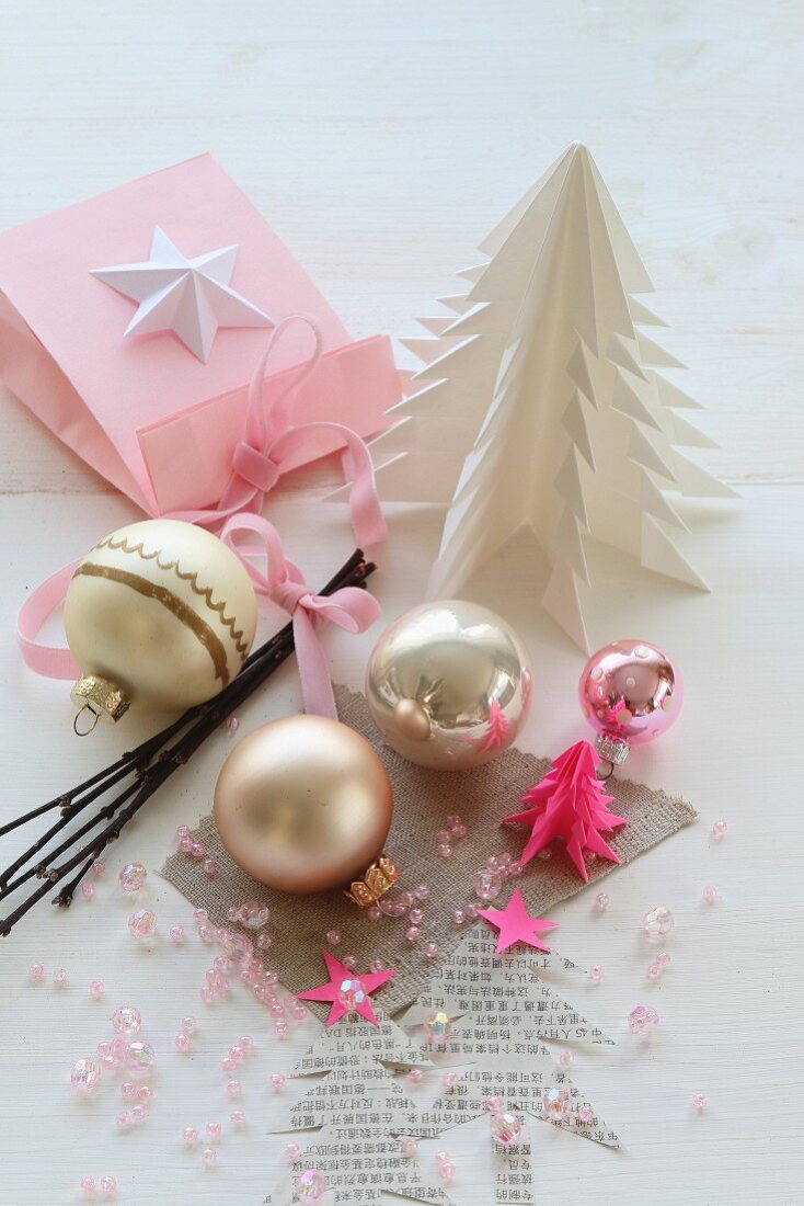 Christmas baubles and pink beads amongst hand-crafted paper Christmas trees