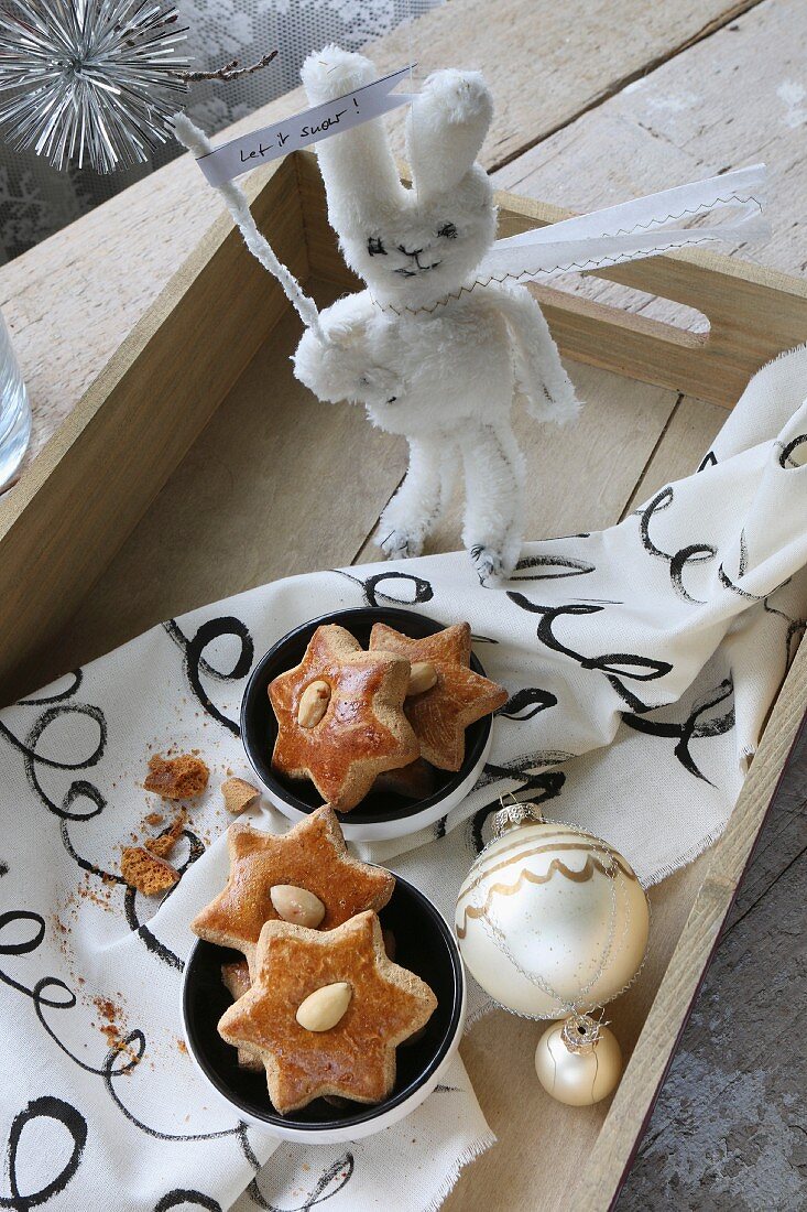 Star-shaped gingerbread biscuits in bowls on hand-painted fabric; hand-sewn soft toy rabbit holding sign